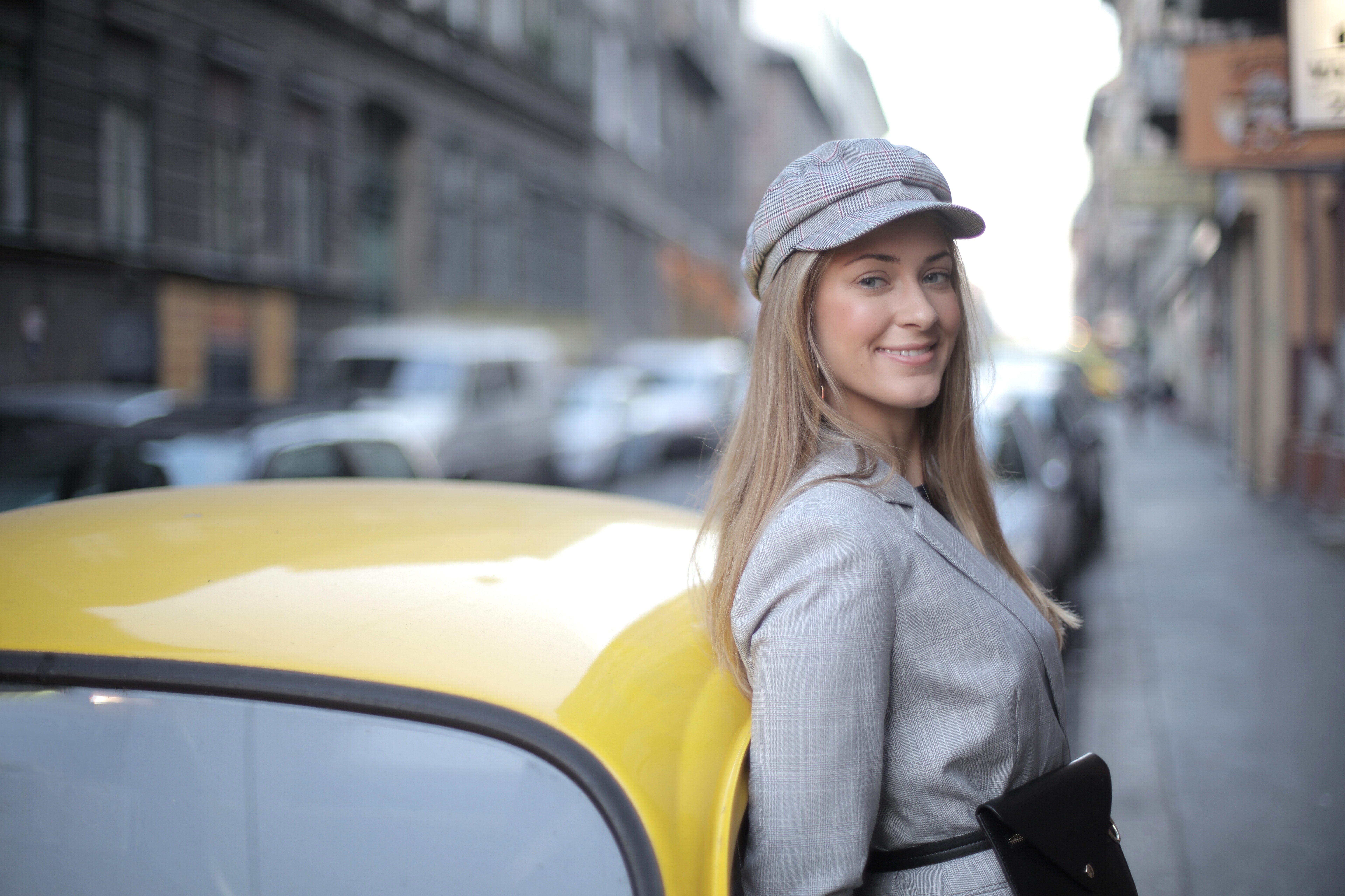 Woman wearing a cap standing beside car.